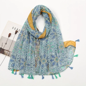 Detailed flat lay of a blue-green ethnic print cotton scarf with fringe and floral decor