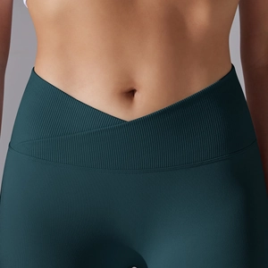 Detail of high-waisted crossover V-waist yoga leggings in dark teal breathable fabric