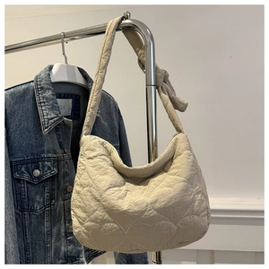 Detail of beige quilted shoulder bag with heart patterns and a stylish knotted strap