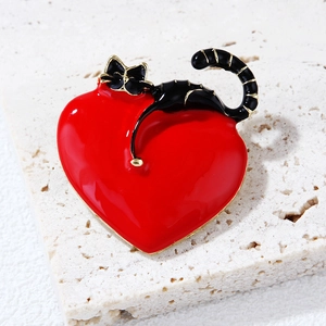 Macro shot of an enamel cat and red heart brooch with fine gold metallic outlines