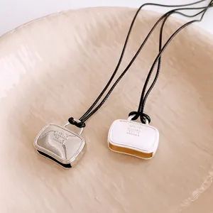 Minimalist wax cord necklace with bag-shaped pendants in silver and white colors
