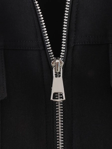 Close-up of the silver metal zipper and black twill fabric on the sleeveless jacket