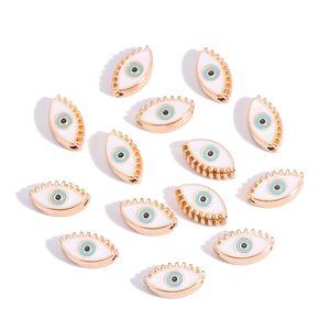 Detailed view of 10mm golden devil eye charms with white enamel and blue eye patterns