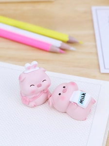 Close-up of cute pink resin pig figurines with rabbit ears and milk bottle on a desk