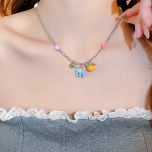 Girl wearing a silver chain necklace with colorful elephant and flower charms