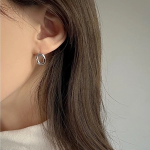 Close-up of minimalist silver irregular round earrings worn by a model in a side view
