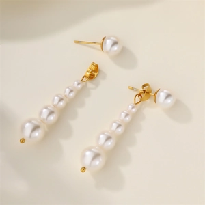 Detail of elegant gold-tone pearl earrings featuring long drop tassel and stud design