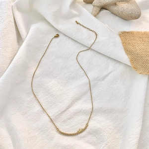 Golden crown and heart necklace with curved bar pendant on a minimalist textured background