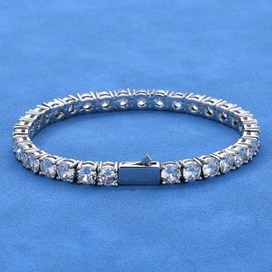 Macro shot of silver tennis bracelet with round-cut white stones on a blue background