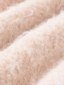 Macro shot of fluffy cream lace-knit fabric showing soft mohair wool texture details