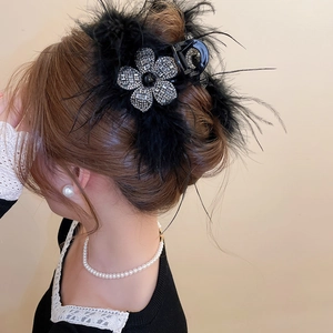 Détail d'une pince à cheveux de luxe en plumes noires avec fleur en strass étincelants