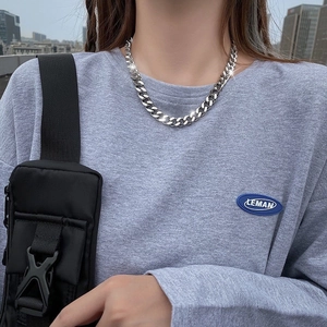Silver cuban link titanium steel necklace worn on neck with urban outdoor backdrop