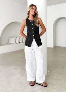 Detail of black denim vest with white crochet lace wide-leg pants on elegant model