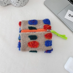 Detail of plush square pouch with colorful polka dots showing zipper and fuzzy texture