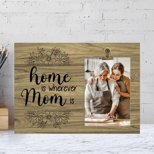 Detail of wooden picture frame with metal clip and engraved home is wherever Mom is text