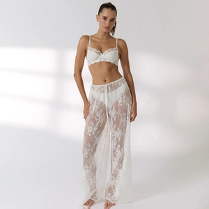 Detailed close-up showing the intricate white floral lace texture on wide-leg trousers