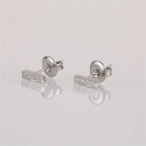 Macro detail of silver stainless steel bar earrings with a hammered texture and butterfly back