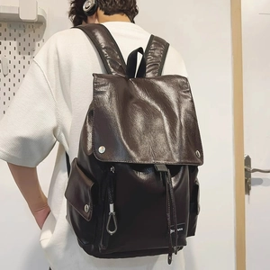 Dettaglio dello zaino in ecopelle marrone scuro con fibbie metalliche e chiusura a coulisse