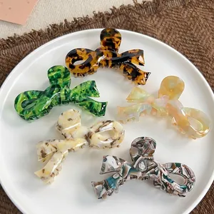 Large acetate bow claw clips in tortoise and marble patterns on a white plate