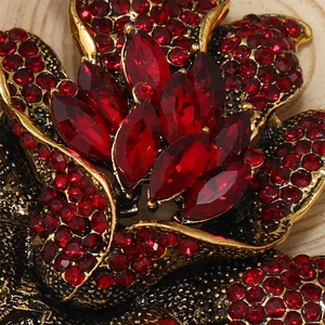 Macro detail of vintage gold flower brooch with radiant red crystals and ornate metalwork