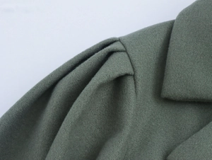 Detailed close-up of wool texture and suit collar stitching on retro pea green coat