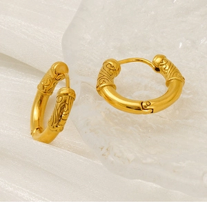 Detail view of gold earrings with engraved retro cloud patterns and clip closure