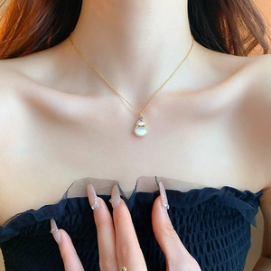 Detailed view of a gold plated gourd necklace with cat eye stone worn on a model neck