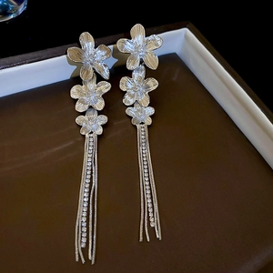 Detail of silver flower tassel earrings with sparkling rhinestones and brushed metal finish