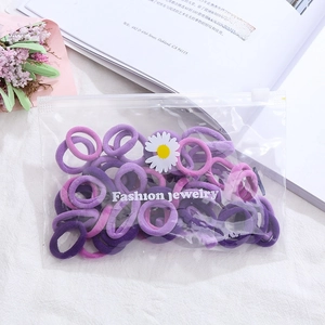 Macro shot of purple elastic hair bands in a daisy zipper bag on a cozy white desk