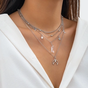 Detail of multilayer silver necklace with star, moon charms and clear crystal pendant
