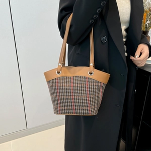Retro canvas bucket bag with brown leather trim and classic plaid pattern held by model