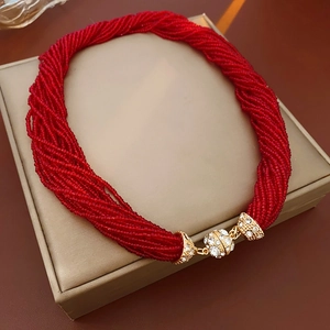 Dettaglio della collana a più fili di perline rosse con chiusura di cristalli