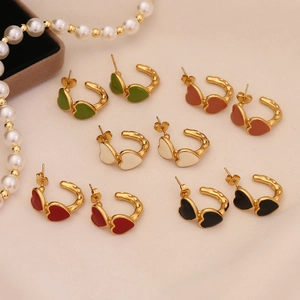Detail of colorful heart-shaped earrings in red, black, green, and cream with gold borders