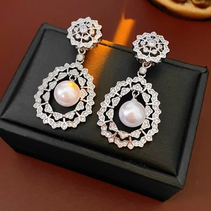 Detail of silver filigree earrings with sparkling cubic zirconia and white pearls on a box
