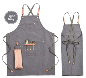 Detail of grey canvas apron with orange stitching, metal hardware, and storage pockets