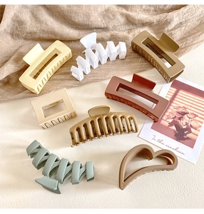 Flat lay of resin hair claws in beige brown and green on a soft fabric background