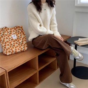 Foto de estilo de vida con pantalón de pana, jersey de punto y bolso de flores naranja