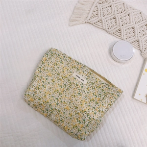 Detailed close-up of yellow floral cotton makeup bag with simple wish label and zipper