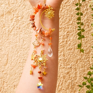 Detail of moon suncatcher with orange crystals, stars, and golden moon pendant