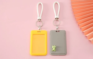 Detail of cartoon card holders with woven lanyards and green dinosaur charms