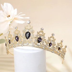 Close-up of golden crown with purple teardrop crystals and fine white rhinestones