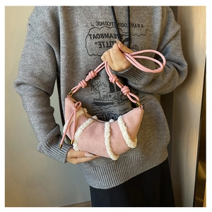 Detail showing pink suede dumpling bag with white faux fur trim and knotted strap