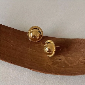 Polished gold dome stud earrings with twisted rope border on textured wood base