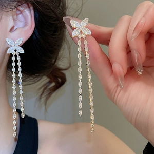 Macro detail of long butterfly tassel earrings with marquise-cut stones and silver plating