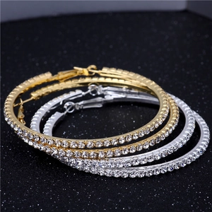 Macro shot of oversized gold and silver hoops featuring sparkling crystal embellishments