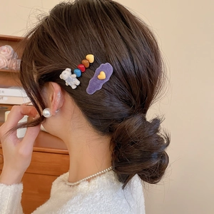 Detail view of cute flocked bear and heart hair clips worn on the side of wavy hair