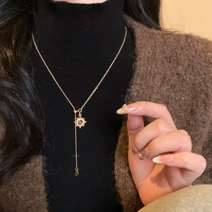 Detailed view of sun pendant necklace with tiger eye stone worn on a model's neck