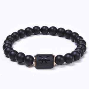 Detailed close-up of matte black onyx bead bracelet featuring a rose gold Pisces zodiac charm