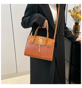 Brown crocodile pattern handbag featuring a gold metal SS logo and stylish tassel detail
