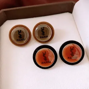 Vintage round acrylic stud earrings with velvet trim and elegant logo detailing